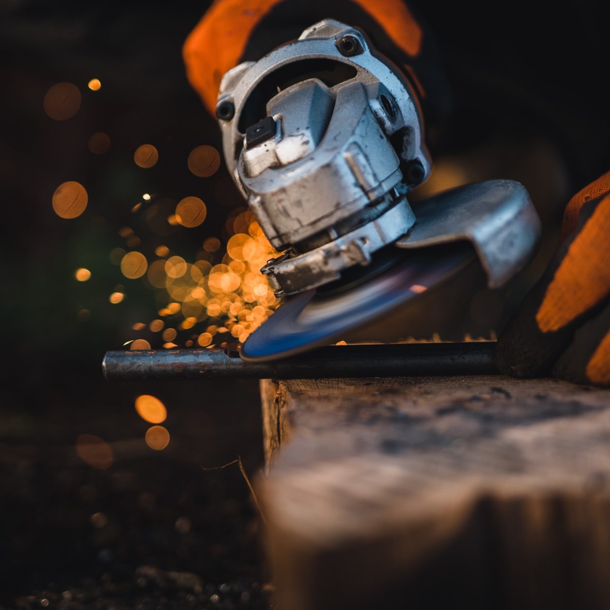 The hands of the master saw the metal with a grinder. Metal works in the workshop close up. Metal processing with angle grinder. Sparks in metalworking.